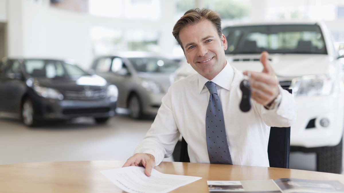 Traditional car dealership showroom with a salesperson discussing pricing with a customer